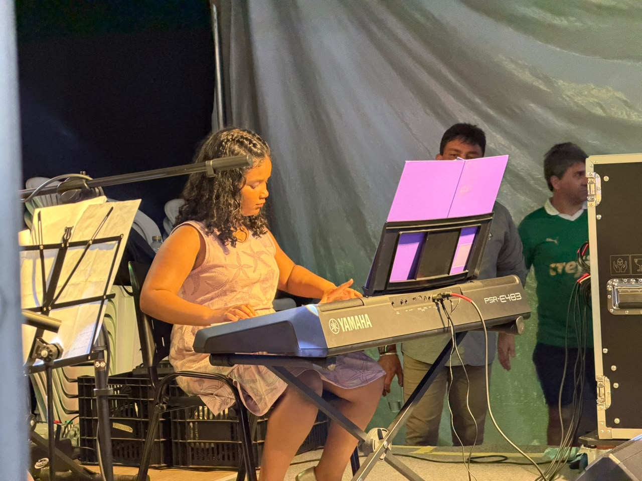 Aluna tocando teclado no palco
