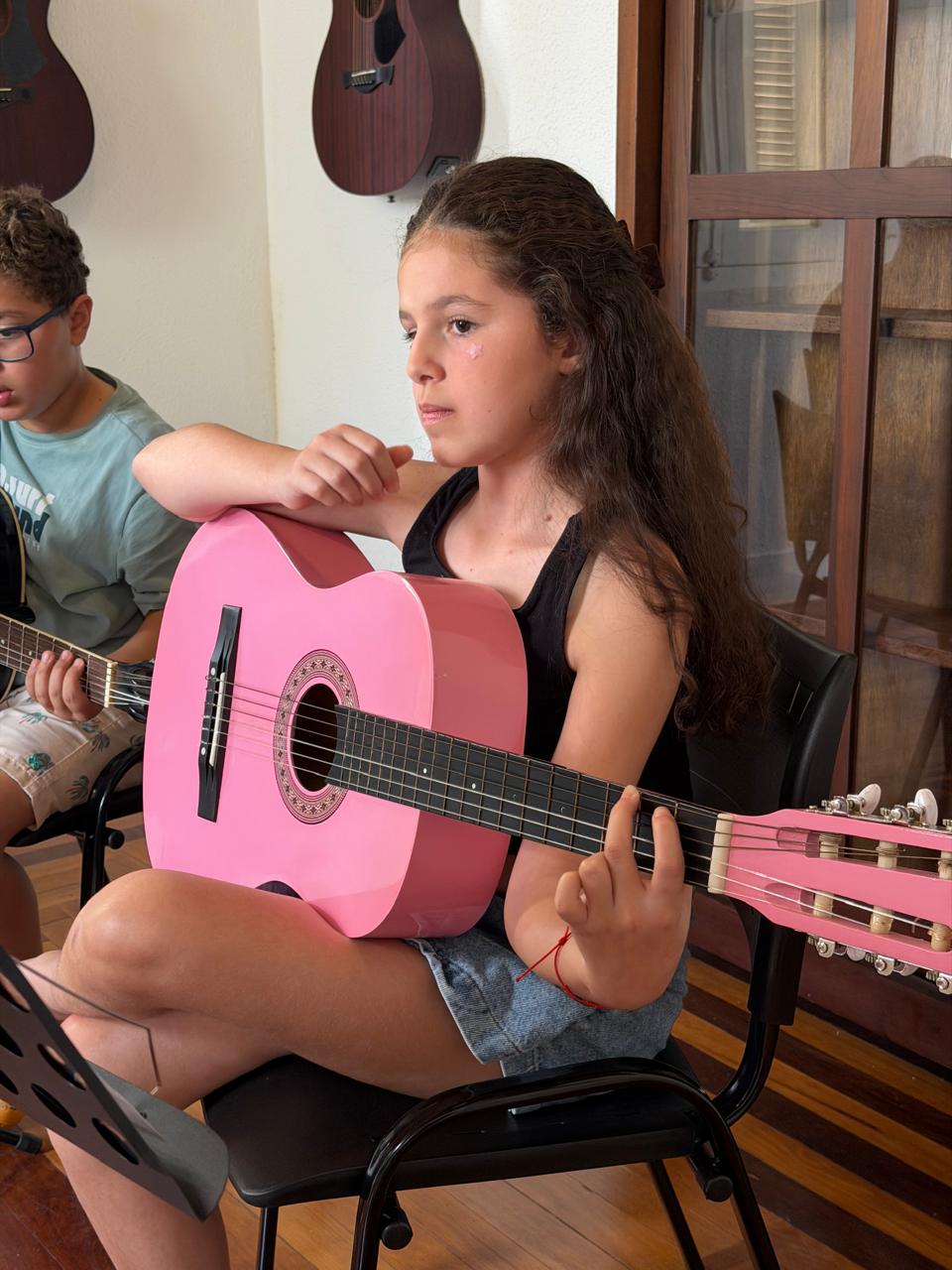 Aluna com violão rosa durante a oficina